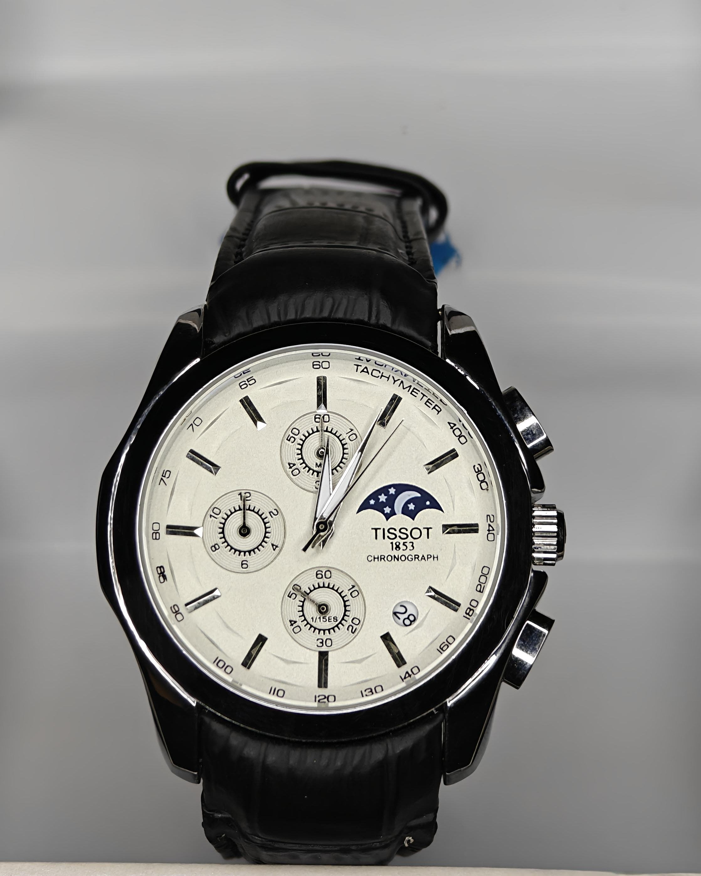 Tissot watch with a white face and black leather strap on a Tissot branded background